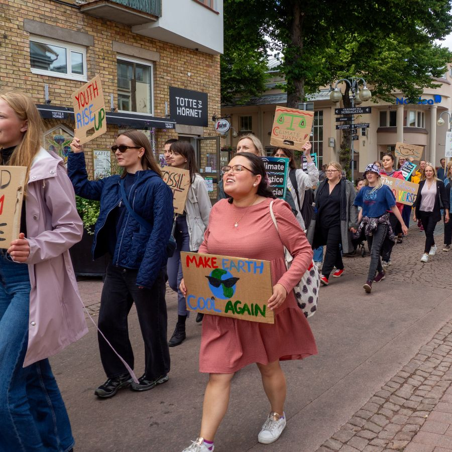 Ungdomar med skyltar i händerna går i ett demonstrationståg för klimatet. 
