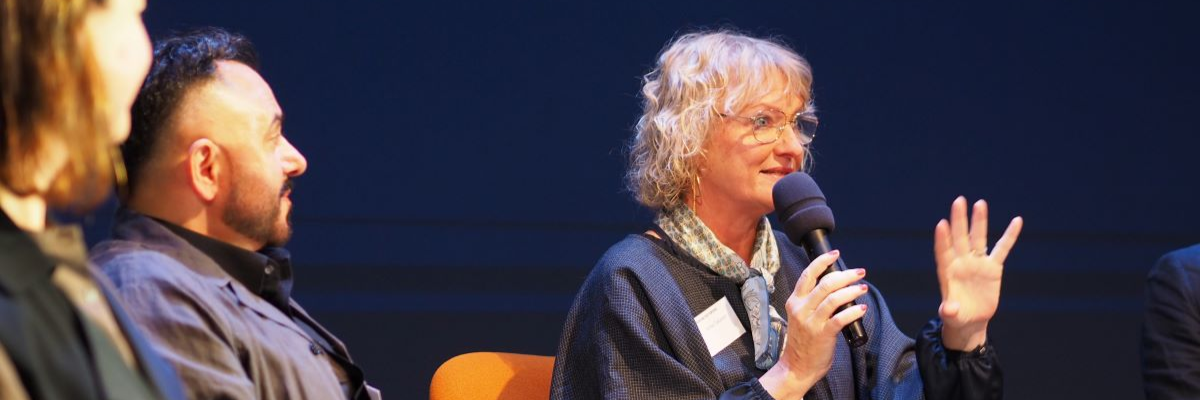 En kvinna talar i mikrofon och gestikulerar med handen