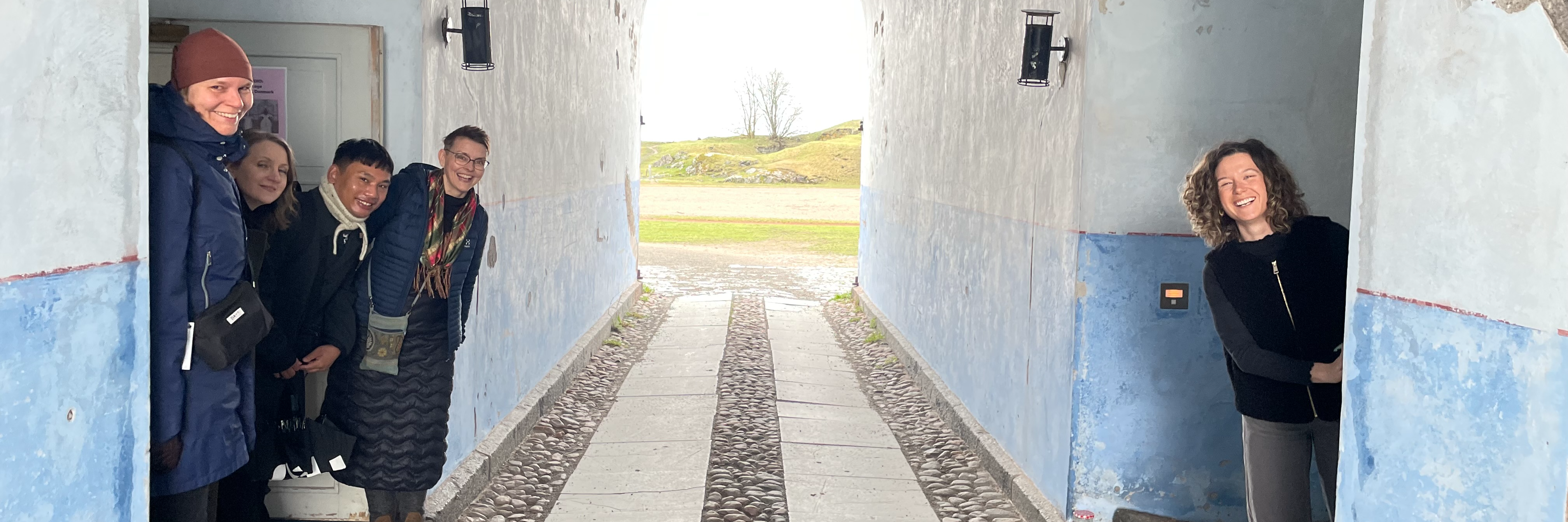 Kvinnor och män kikar ut från dörrar i en gång