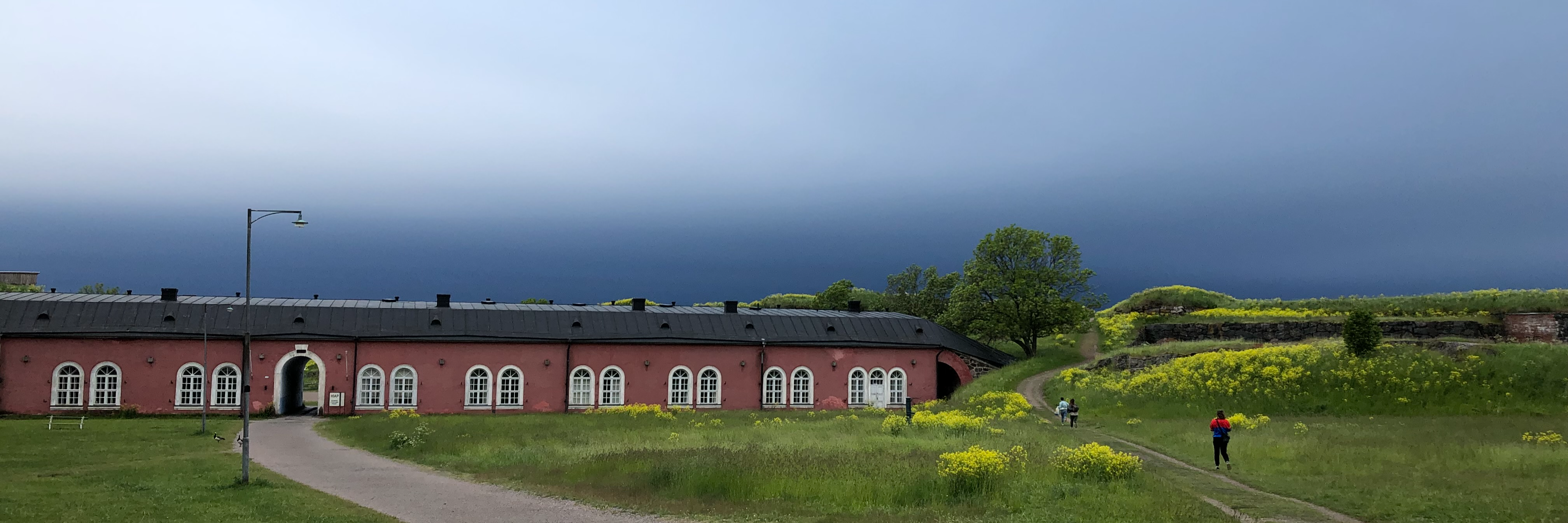 Rosa byggnad med gula blommor framför. 