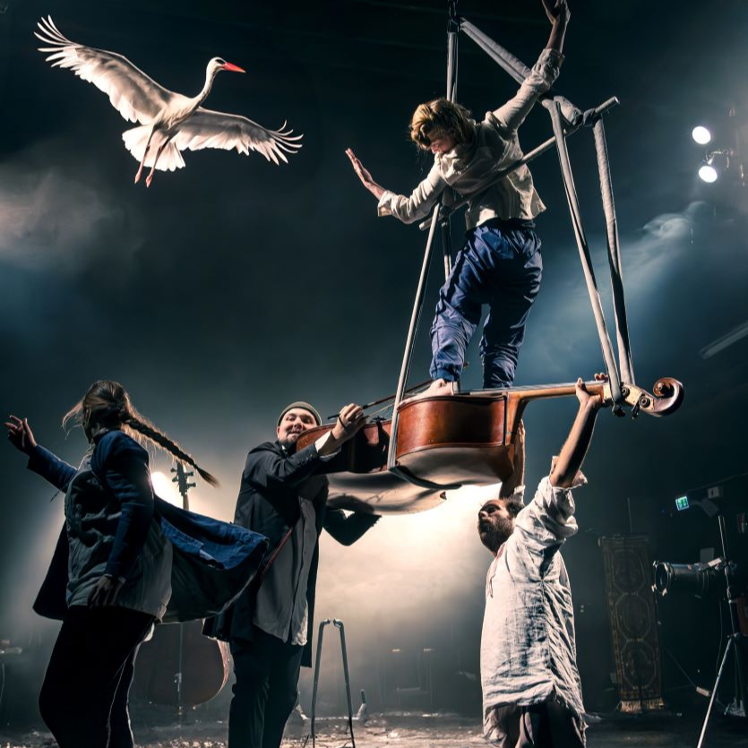 Cirkusperformans där en person står på en upplyft kontrabas